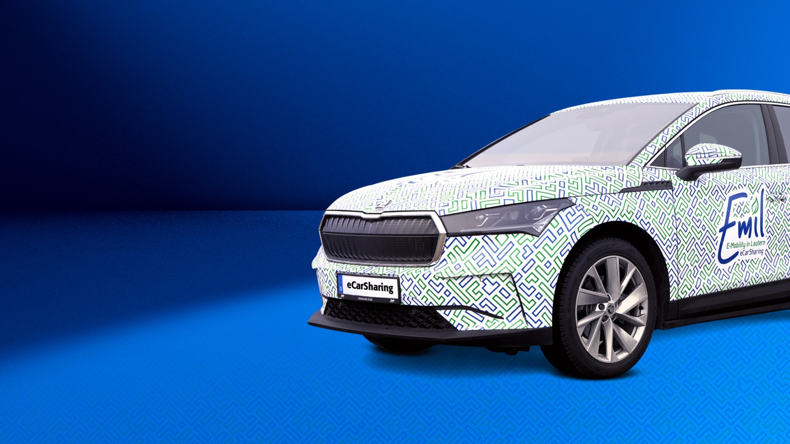 Skoda Enyaq mit Emil eCarSharing-Branding auf blauem Hintergrund ragt rechts bis zu Hälfte ins Bild hinein.